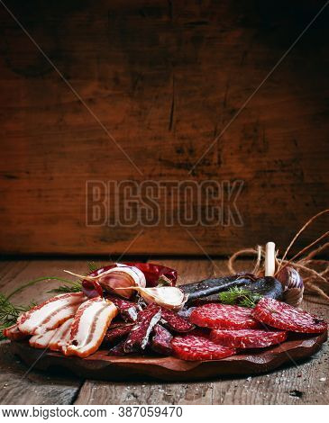 Meat Appetizer Platter With Bacon, Smoked Sausage And Salami On A Wooden Cutting Board, Selective Fo