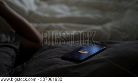 Close Up Of Sleeping Man Being Woken Up By His Phone Lying On The Bed. Concept. Male Hand Trying To 