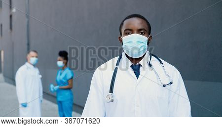 Portrait Of African American Young Man Doctor In Medical Mask And With Stethoscope Looking At Camera