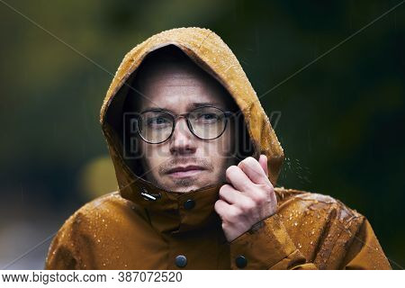 Heavy Rain During Autumn Day. Portrait Of Young Man In Waterproof Jacket.