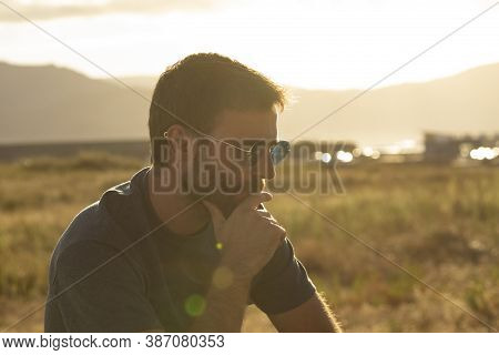 A Young Man, Wearing Glasses, Concentrating On Himself, Meditates In A Relaxed Way, While Enjoying T