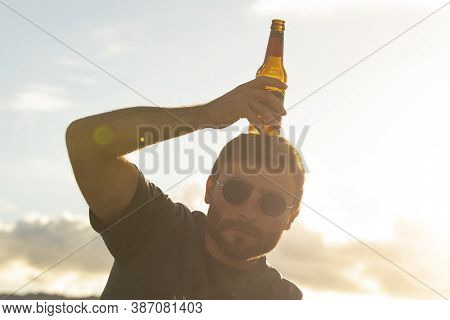 A Young Man, With Glasses, Does Silly Things, While Drinking Beer From A Bottle, Enjoying The Sunset