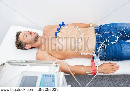 Mature Man Getting Electrocardiogram In A Hospital Room. Procedure Ecg In Clinic