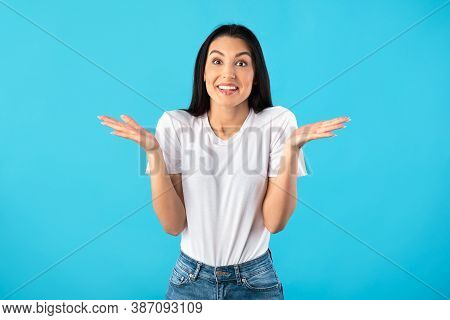 Who Knows. Portrait Of Positive Young Woman Shrugging Shoulders Smiling To Camera Posing Over Blue B