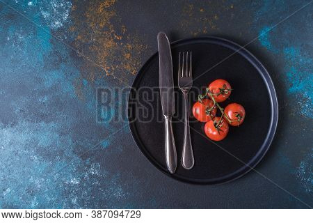 Red Ripe Tomatoes And Cutlery On A Plate.