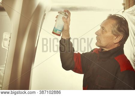 Man Spraying And Repairing In Basement Car Fender For Replacing