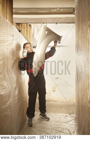 Man Spraying And Repairing In Basement Car Fender For Replacing