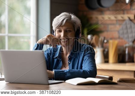 Smart Elderly Woman In Headphones Watch Webinar On Laptop