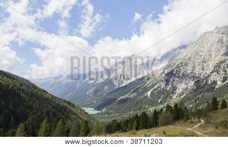 Krajina Hochgall horské vrcholky mraků, údolí a jezera v italských Alpách.