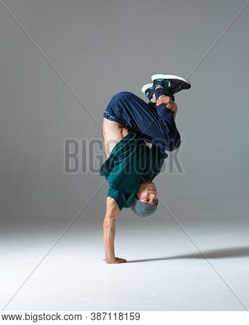 Cool Guy Breakdancer Stands On One Hand Dancing Lower Break Dance Isolated On Gray Background. Break