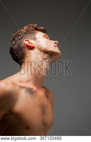 Portrait Of Handsome Young Guy With Stylish Haircut Without Shirt Standing In Studio. Body With Tatt