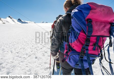 Rope Team Member Point Of View With Mountaineers Walking On Snow And Ice In Sunny Weather.
