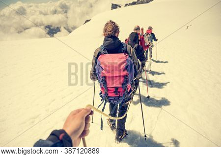 Rope Team Member Point Of View With Mountaineers Walking On Snow And Ice In Sunny Weather.