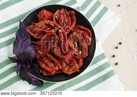 Top View Of Plate With Sun-dried Tomatoes In Olive Oil, With Spices And Basil Leaves Closeup
