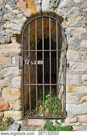 Old Closed Rusty Iron Gate In Arch Door Of Castle Brick Wall