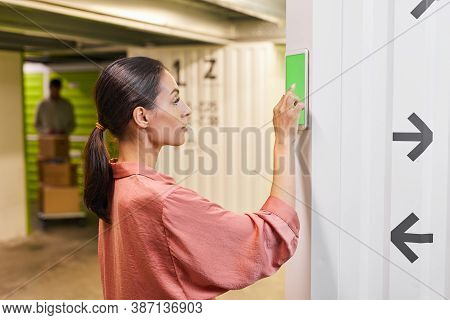 Side View Portrait Of Young Woman Using Touch Pad With Green Screen While Operating Self Storage Uni
