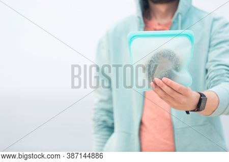 Man Holding Silicone Reusable Snack Bag With Food Inside, Zero Waste Concept, Aqua Menthe Is Year 20