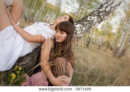 Two Girls Sit Near Birch