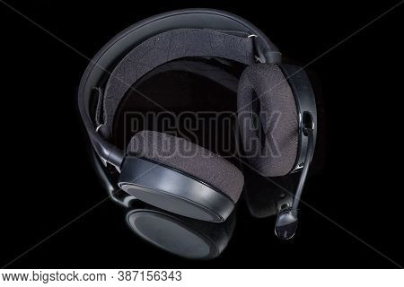 Black High-fidelity Headset With Earpads Of Circumaural Type And Microphone On A Dark Reflective Sur