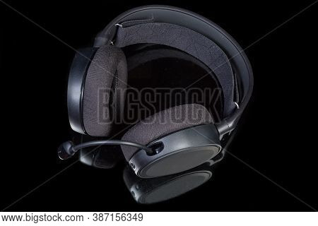 Black High-fidelity Headset With Earpads Of Circumaural Type And Microphone On A Dark Reflective Sur