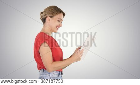 Woman In Casual Clothing Using Digital Tablet Walking On Gradien