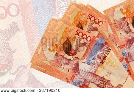 5000 Kazakhstani Tenge Bills Lies In Stack On Background Of Big Semi-transparent Banknote. Abstract 