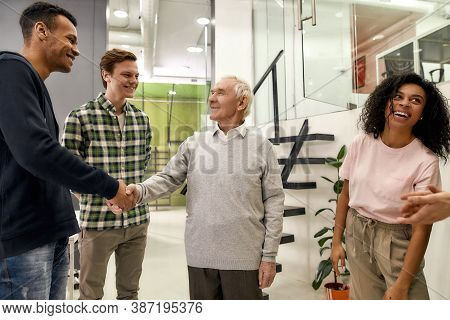 Cheerful Young Team Greeting New Worker In The Modern Office, Aged Man Or Senior Intern Shaking Hand