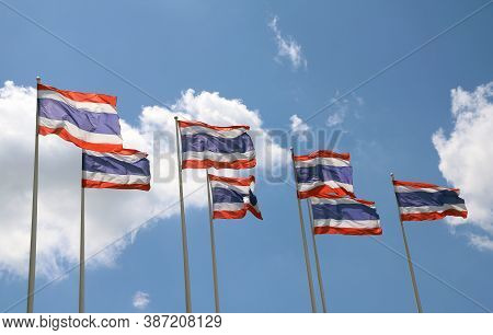 Seven Thai National Flag On Bright Blue Sky Background. Blown Away By Wind.