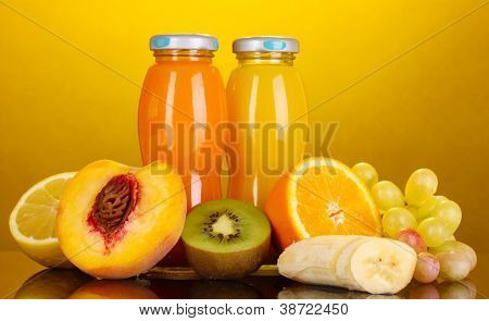 Succo Multifrutta delizioso in una bottiglia e frutta accanto ad essa su sfondo giallo