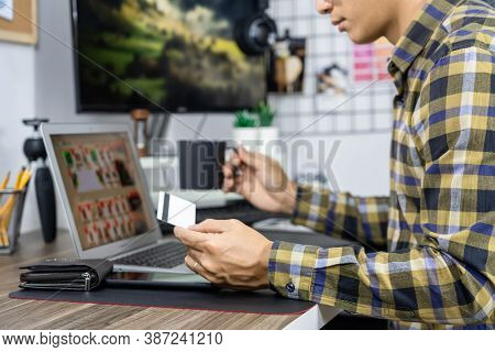 Asian Man Holding Credit Card And Typing Information On Internet With Laptop At Home, Online Shoppin