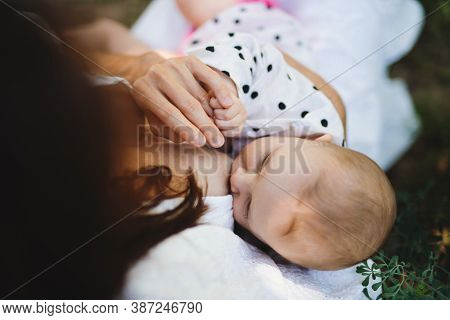 Top View Of Woman Nursing Baby Girl Outdoors In Backyard.