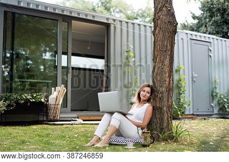 Mature Woman Working In Home Office Outdoors In Garden, Using Laptop.
