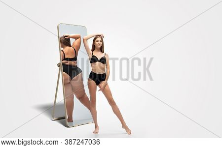Young Fit, Slim Woman Looking At Fat Girl In Mirrors Reflection On White Background. Thinking Shes N