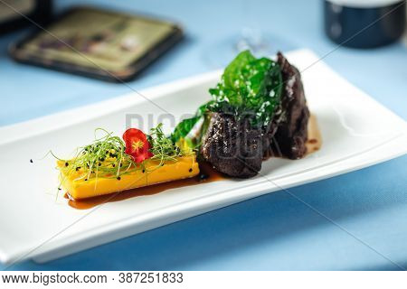 Spanish Veal Cheeks In Wine Sauce And Sweet Potato Puree With Wine Bottle On The Background