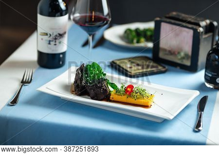 Spanish Veal Cheeks In Wine Sauce And Sweet Potato Puree With Wine Bottle On The Background