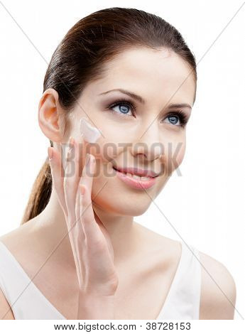 Mujer de aplicar la crema en el rostro, aislado en blanco. La búsqueda de la belleza