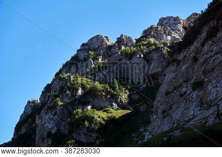 Beautiful Cliff Ledges With Grass And Trees Against Blue Sky
