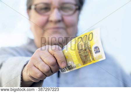Satisfied, An Elderly Adult Woman Gives A Currency Of Close-up 200 Euros. Mature Woman And Holds Out