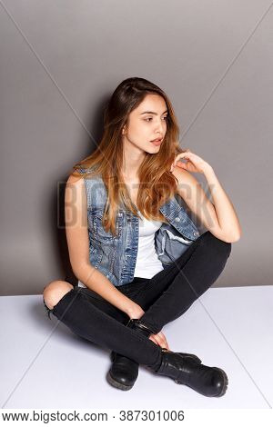 Full Length Image Of A Young Woman In Stylish Outfit Poses With Attitudine In Studio Seated Down, Gr