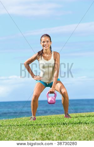 Fitness Übung Frau heben Kettlebell während Stärke Training trainieren im Freien auf g
