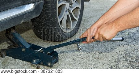 Man Changing Wheel. Tire Changer Changing Flat Car Tire. Help On Road Concept. Mechanic Hands Unscre