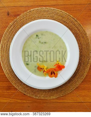 Top View Of Green Soup With Comestible Flowers.