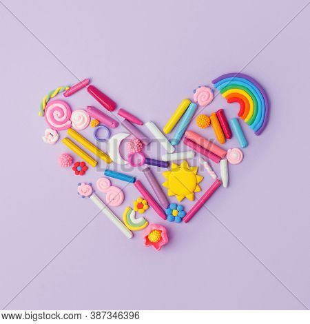 Heart From Many Kids Accessories From Clay, Wax Chalk On Purple Pastel Background, Concept Of Pop Ar