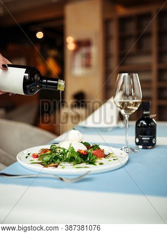 Pouring Oil On Spanish Buratta Salad On The Restaurant Table