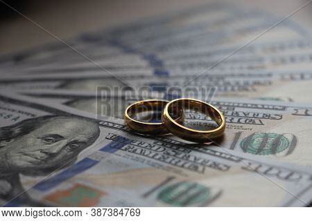 Wedding Rings On The Background Of 100 Dollars Bills. Marriage Conctract Or Prenuptial Agreement Con