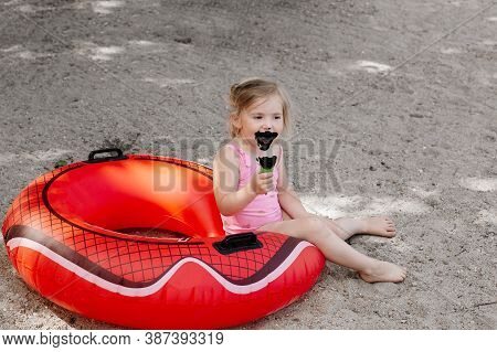 Little Girl Eating Black Ice Cream On The Beach. Lifebuoy. Dirty Child
