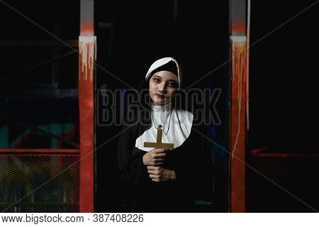 Scary Woman Devil Nun Holding A Cross. Horror Halloween Concept