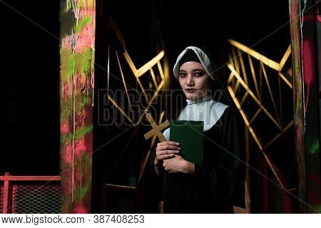 Scary Woman Devil Nun Holding A Cross. Horror Halloween Concept