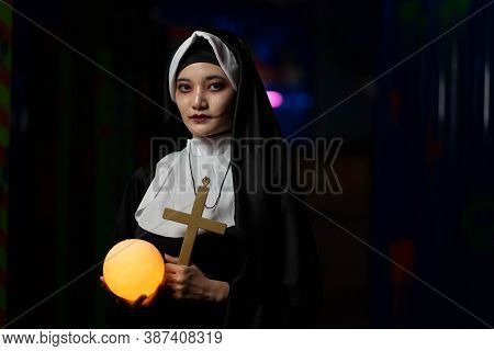 Scary Woman Devil Nun Holding A Cross. Horror Halloween Concept