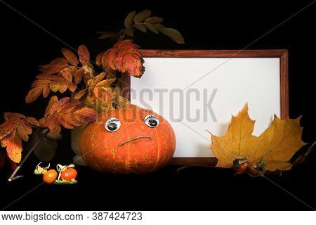 Portrait Empty Wooden Frame Mockup. Pumpkin With Eyes, Maple And Rowan Leaves. Black Background. Tha